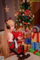 A woman sitting on a bed next to a christmas tree.