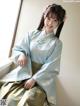 A woman in a blue and gold hanbok sitting on a window sill.