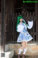 A woman with green hair wearing a blue and white dress.