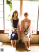 A couple of women standing next to each other in front of a window.