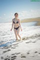 A woman in a bikini walking on the beach.