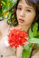 A woman holding a bunch of red flowers in her hand.