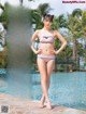 A woman in a bikini standing next to a swimming pool.