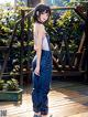 A girl in overalls standing on a wooden deck.