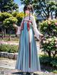 A woman in a blue and white dress standing in a garden.