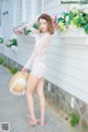 A woman in a white lingerie and a straw hat posing for the camera.